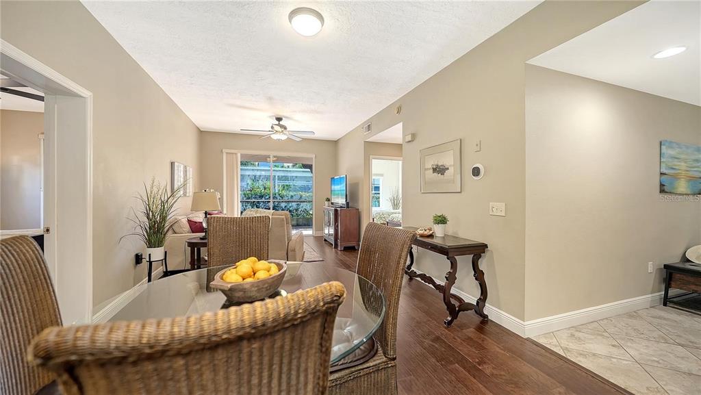 A dining area with a glass table and wicker chairs opens into a living room — 4224 CENTRAL SARASOTA PARKWAY UNIT 1116, SARASOTA, FL