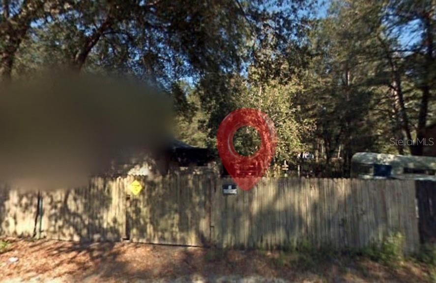 A wooden privacy fence surrounds a property with trees and a parked trailer — 2285 NW 65TH PLACE, OCALA, FL