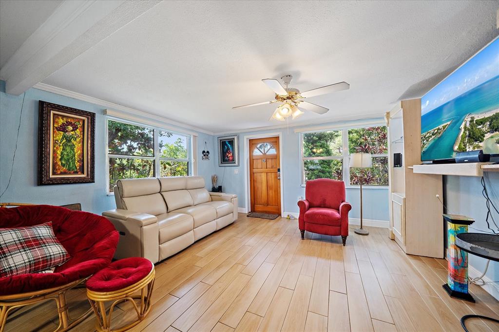 A living room with light blue walls, wood-look tile flooring, a ceiling fan, and furniture — 2503 53RD AVENUE W, BRADENTON, FL