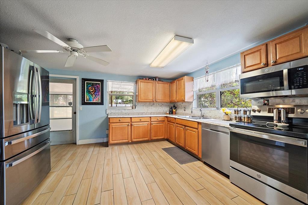 A kitchen with light blue walls, wood cabinets, stainless steel appliances, and wood-look tile flooring — 2503 53RD AVENUE W, BRADENTON, FL