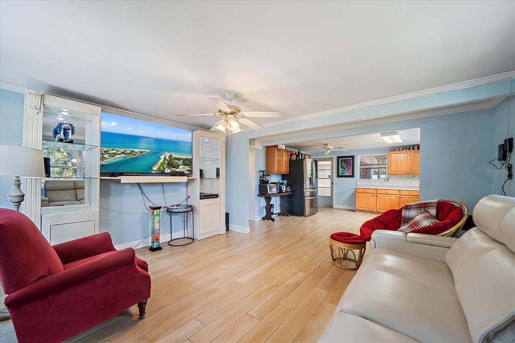 A living room with light wood floors, a red armchair, and an open kitchen area — 2503 53RD AVENUE W, BRADENTON, FL