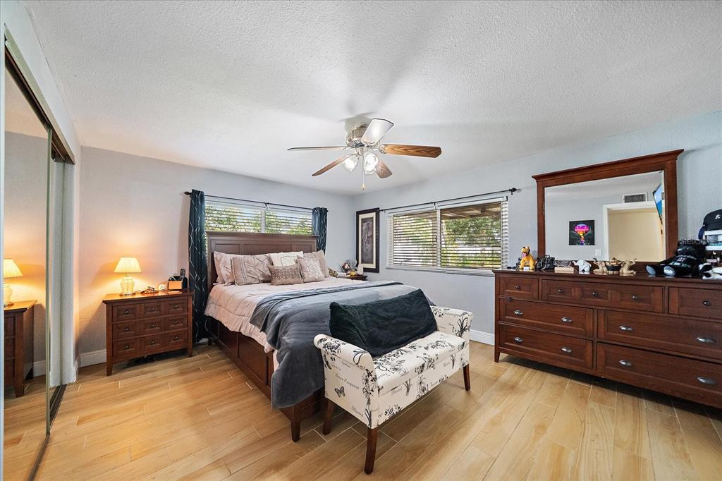 A bedroom features a wooden bed, a dresser with a mirror, and light-colored tile flooring — 2503 53RD AVENUE W, BRADENTON, FL