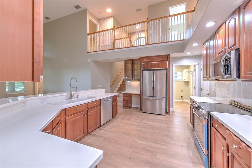 A kitchen with wood cabinets, stainless steel appliances, and a loft overlooking the space — 4812 WALNUT RIDGE ROAD, LAND O LAKES, FL