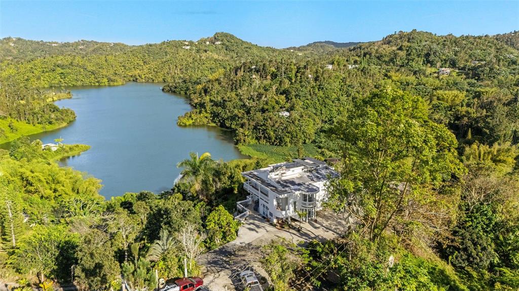 An aerial view shows a white multi-story house situated next to a large lake — Carretera 742 Km.2.3 SECTOR LAS VILLAS BO. CARITE UNIT F2-F3, GUAYAMA, PR