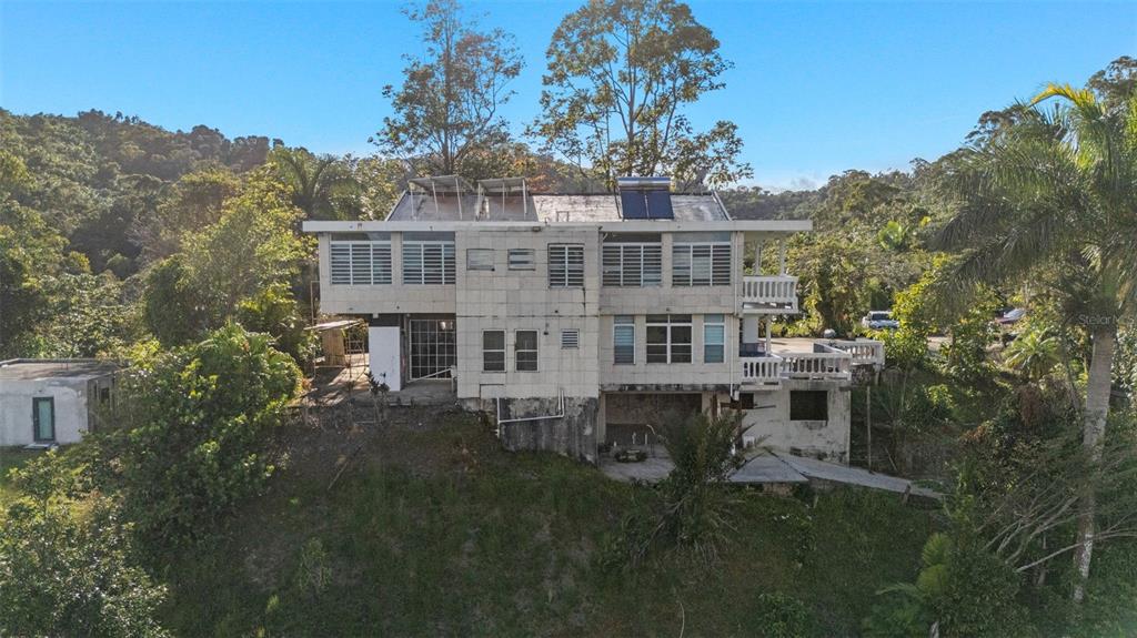 A multi-story house with a tiled exterior sits on a hillside surrounded by lush trees — Carretera 742 Km.2.3 SECTOR LAS VILLAS BO. CARITE UNIT F2-F3, GUAYAMA, PR