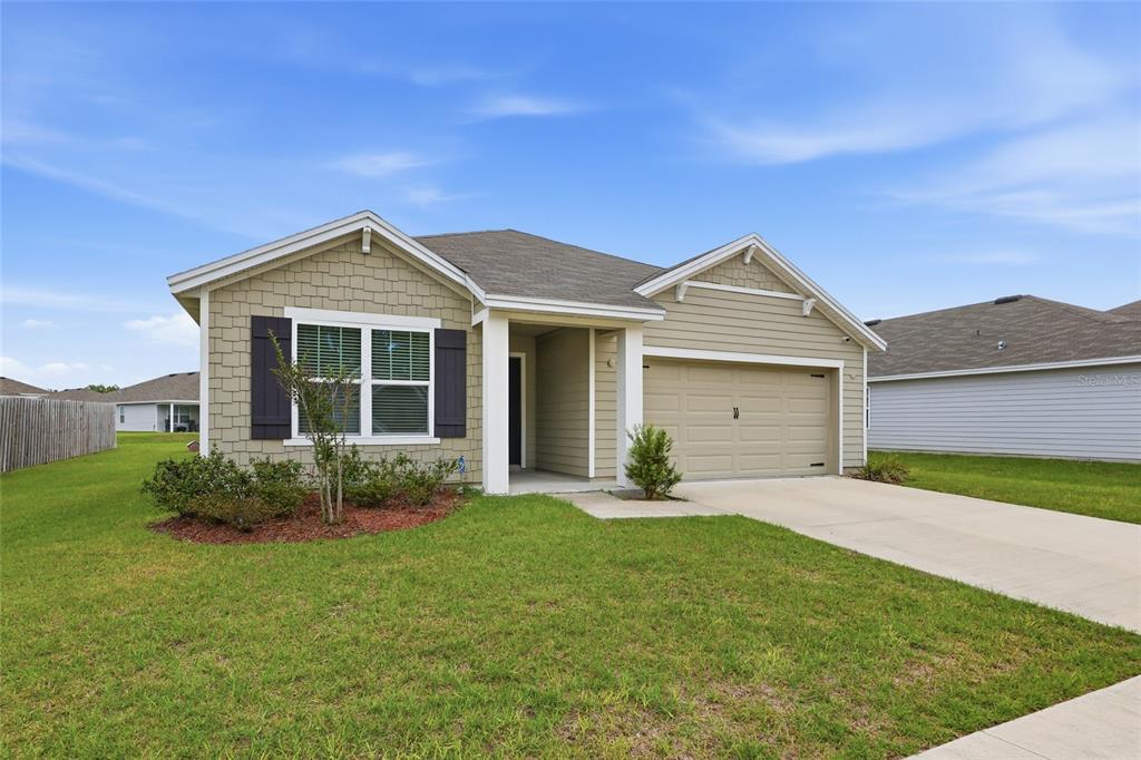 A single-story house with tan siding, a two-car garage, and a front lawn — 19142 NW 164TH ROAD, HIGH SPRINGS, FL