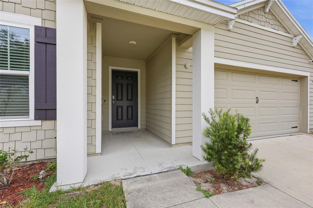 The exterior of a house features a covered entryway, a dark front door, and a garage — 19142 NW 164TH ROAD, HIGH SPRINGS, FL