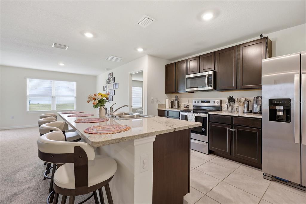 A kitchen features dark wood cabinets, granite countertops, a center island, and stainless steel appliances — 19142 NW 164TH ROAD, HIGH SPRINGS, FL