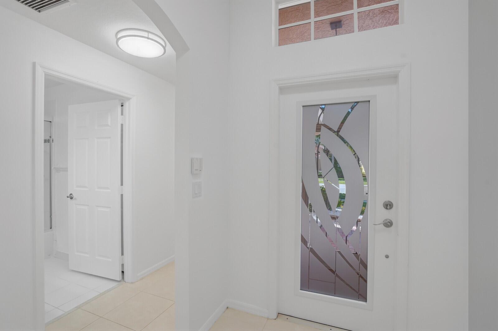 A bright entryway features white walls, tile flooring, a decorative glass front door, and transom windows — 5329 Toscana Trail, Boynton Beach FL 33437, BOYNTON BEACH, FL