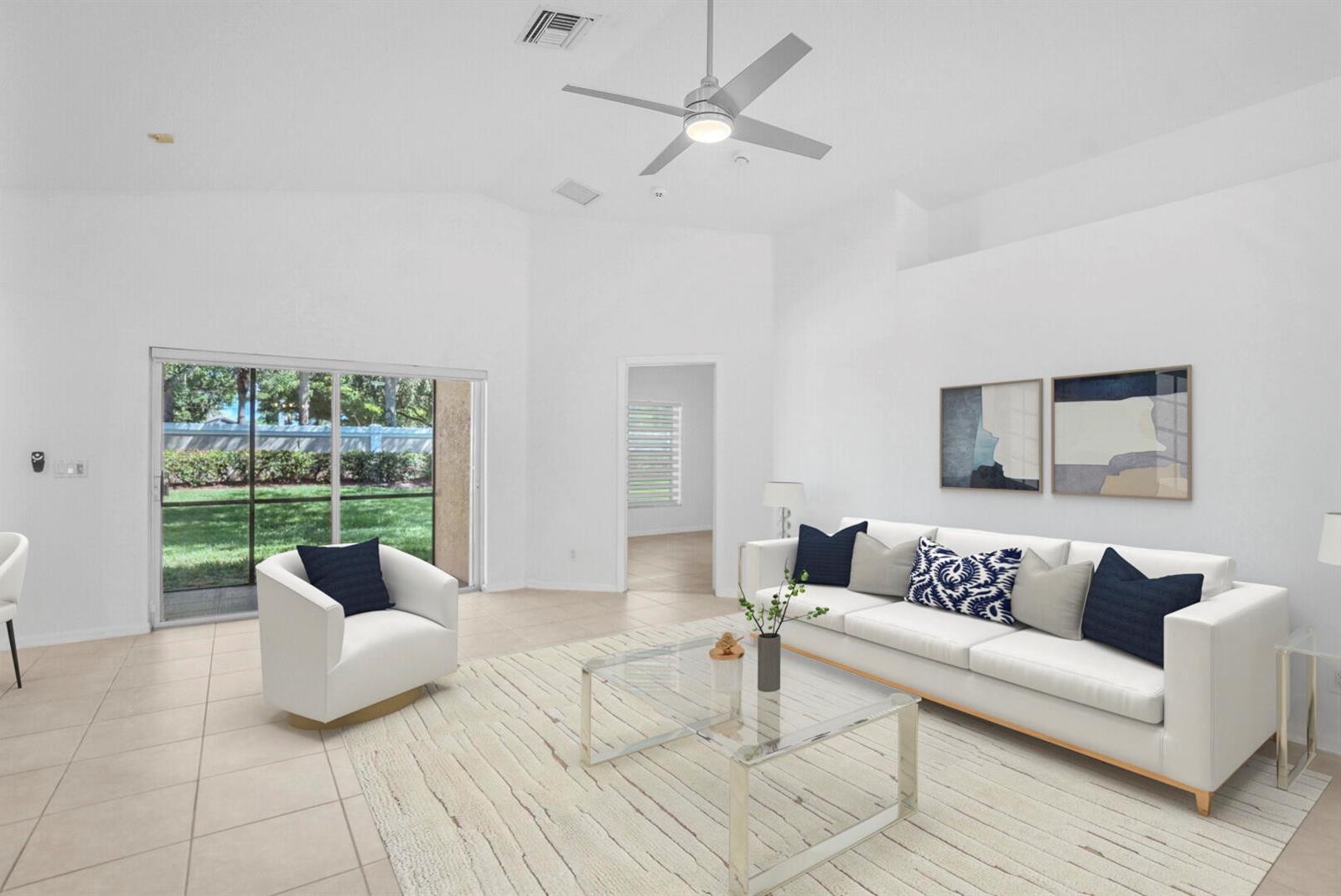 A bright living room features a white sofa, glass coffee table, and sliding glass doors — 5329 Toscana Trail, Boynton Beach FL 33437, BOYNTON BEACH, FL