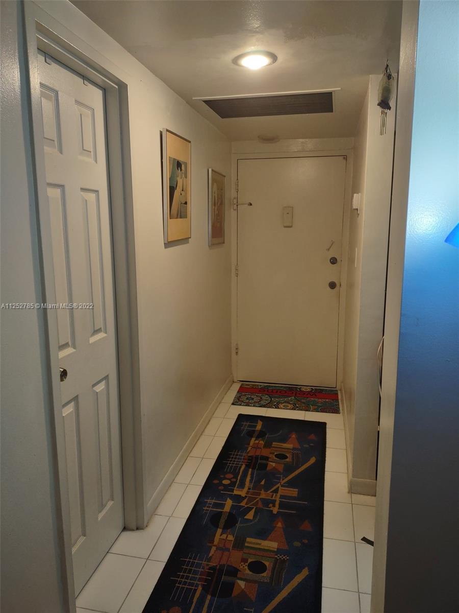 An interior entryway features white walls, a tiled floor, and a patterned runner rug — 4747 Collins Ave # 107, Miami Beach FL 33140, MIAMI BEACH, FL