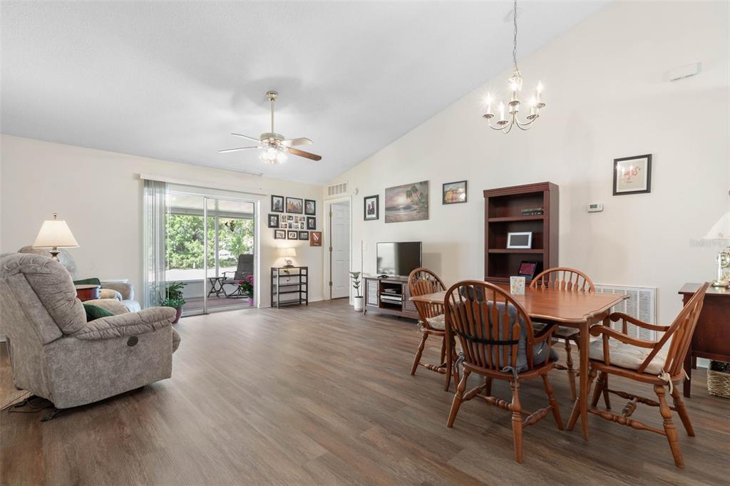 A living and dining area with wood-look flooring, a ceiling fan, and a sliding glass door — 38 LLOYD TRAIL, PALM COAST, FL