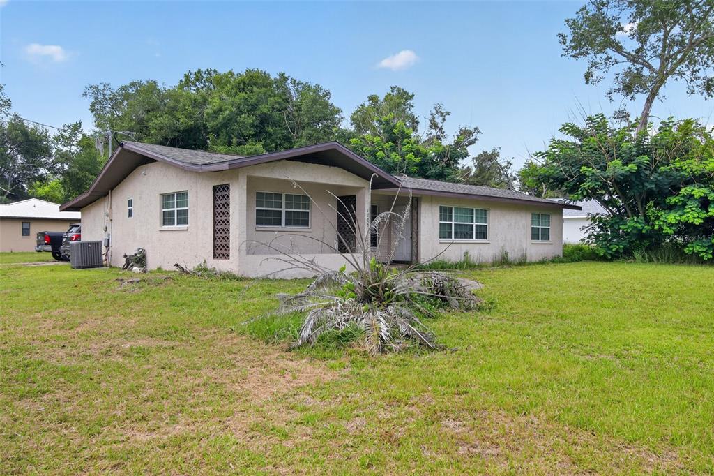 A single-story house with a stucco exterior, a covered porch, and a large grassy yard — 1705 EDEN DRIVE, INVERNESS, FL