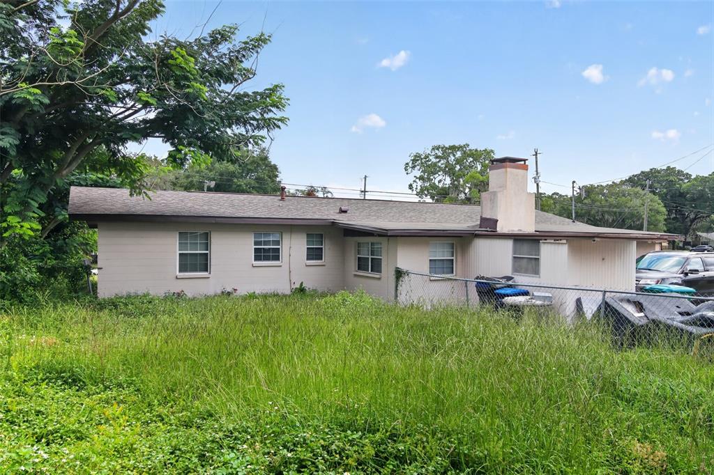 The exterior of a single-story house with a chimney and an overgrown grassy yard — 1705 EDEN DRIVE, INVERNESS, FL