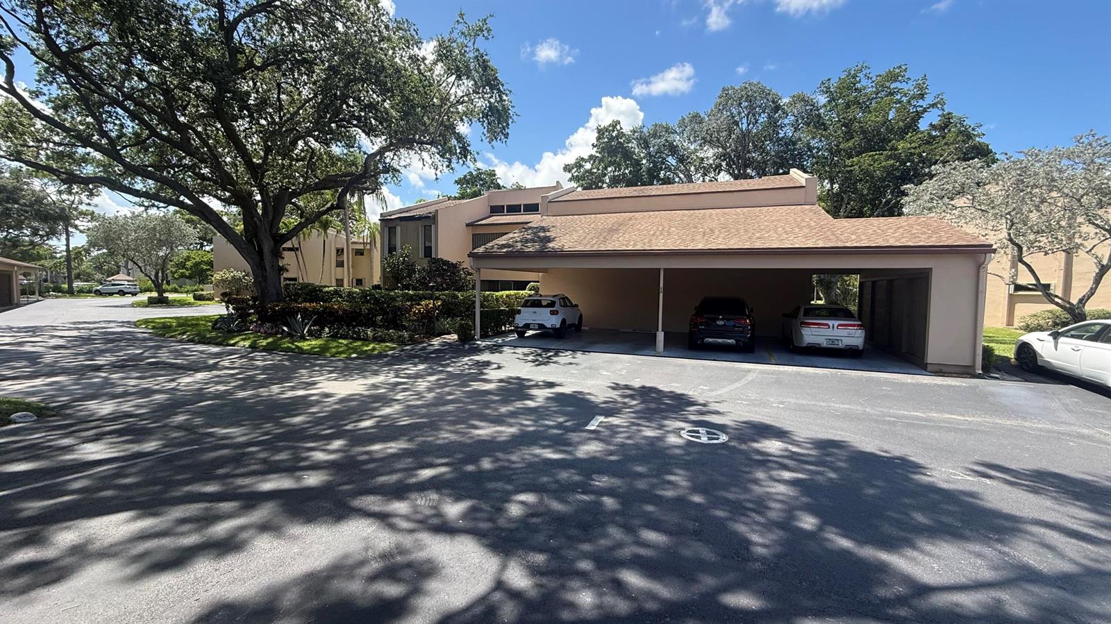 A tan multi-story building features a covered carport with three parked cars — 6474 Pumpkin Seed Circle # 206, Boca Raton FL 33433, BOCA RATON, FL