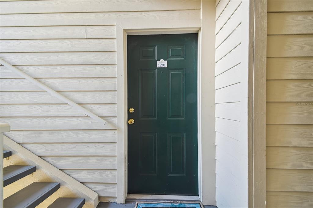 A dark green front door with the number 1201 sits beside an outdoor staircase — 1201 BAY CLUB CIRCLE, TAMPA, FL