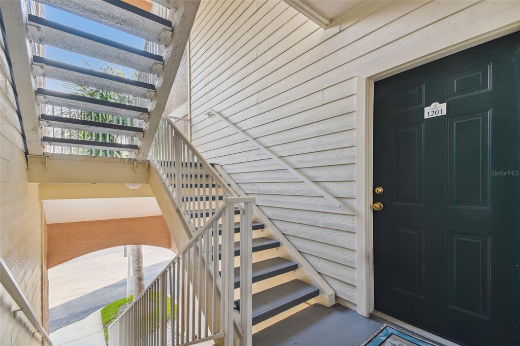 An exterior view shows a dark green apartment door numbered 1201 beside an outdoor staircase — 1201 BAY CLUB CIRCLE, TAMPA, FL