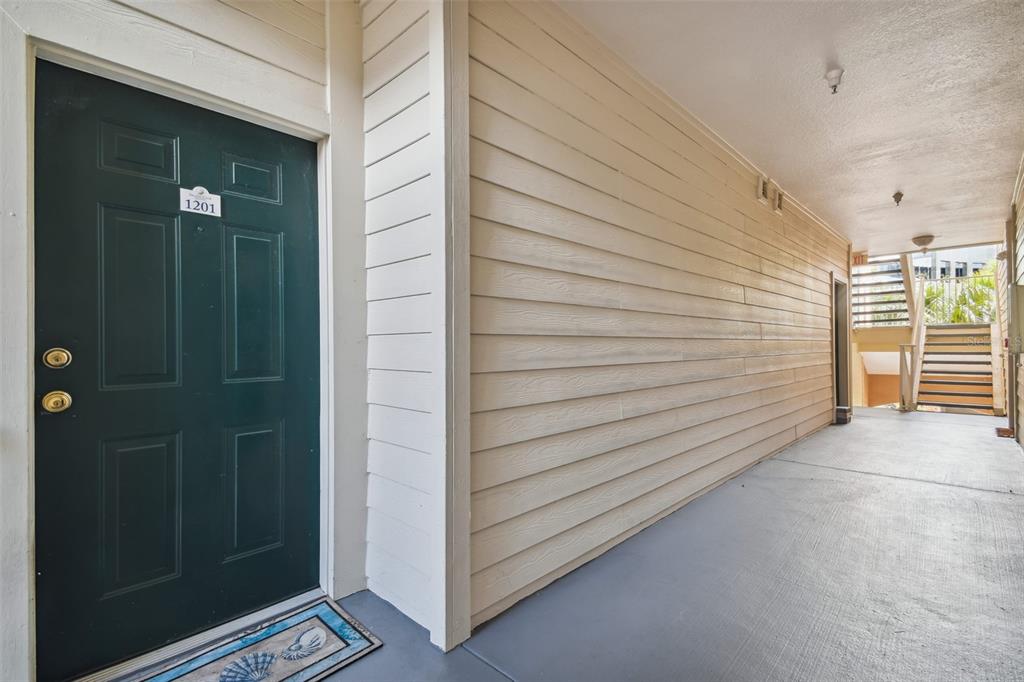 A dark green front door with the number 1201 sits on a covered outdoor walkway — 1201 BAY CLUB CIRCLE, TAMPA, FL