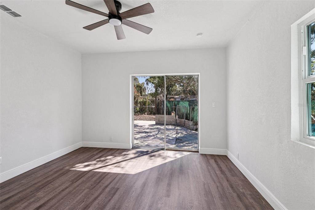 A white kitchen features a central island with a sink and wood-look flooring — 6709 HILL TOP ROAD, ORLANDO, FL