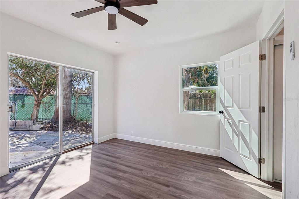 A bedroom with white walls, dark wood-look flooring, a ceiling fan, and an attached bathroom — 6709 HILL TOP ROAD, ORLANDO, FL