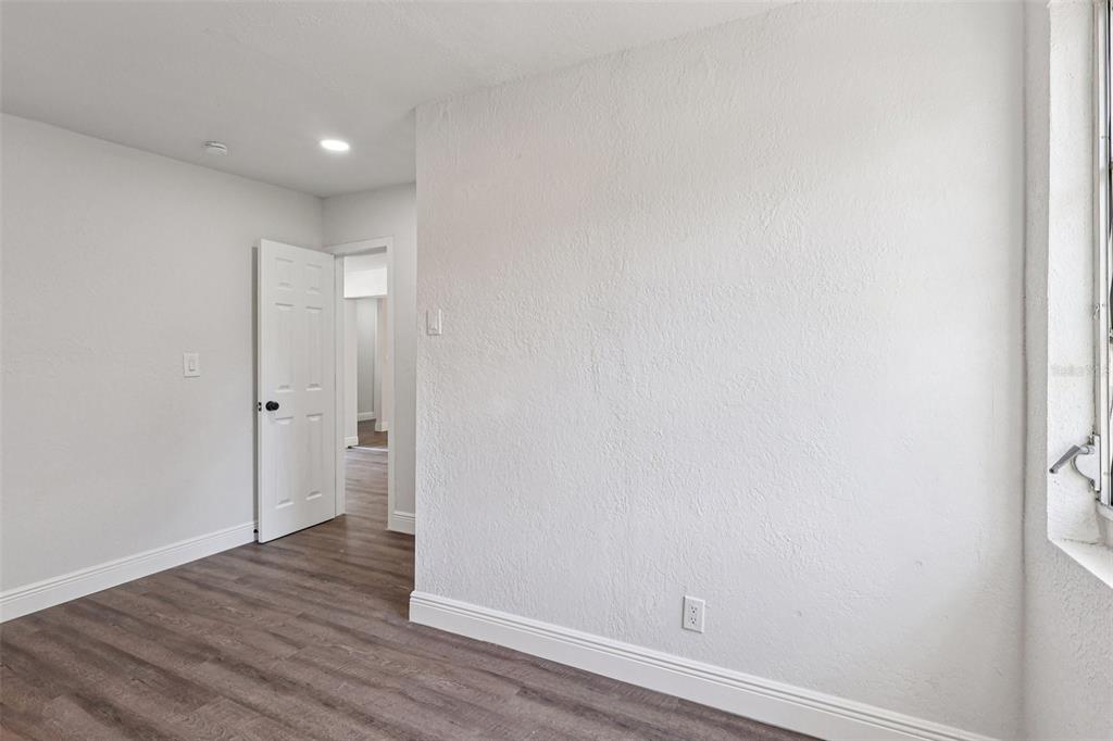 An empty bedroom features wood-look flooring, a ceiling fan, and sliding glass doors to a patio — 6709 HILL TOP ROAD, ORLANDO, FL