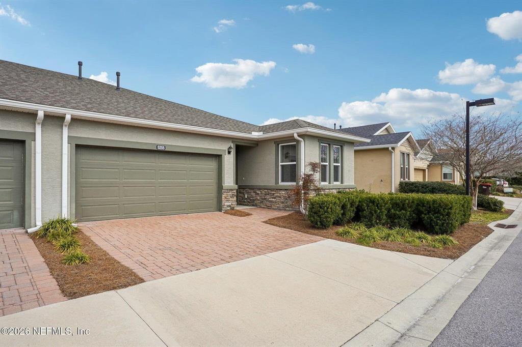A single-story house with a brick driveway, two-car garage, and stone accents on the exterior — 5255 NW 33RD PLACE, OCALA, FL