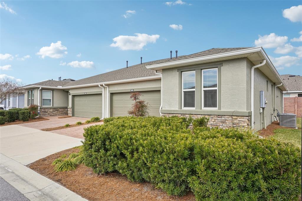 A beige suburban townhouse with a two-car garage and a landscaped front yard — 5255 NW 33RD PLACE, OCALA, FL