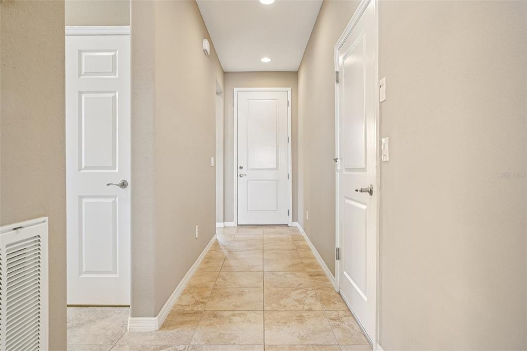 A hallway with beige walls, tile flooring, and three white doors — 5255 NW 33RD PLACE, OCALA, FL