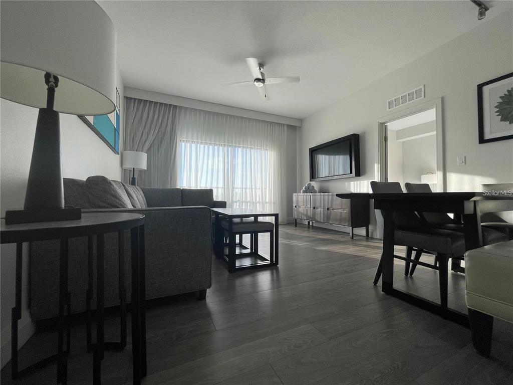 A living room features a gray sofa, dining area, and large windows with sheer curtains — 14501 GROVE RESORT AVENUE, WINTER GARDEN, FL