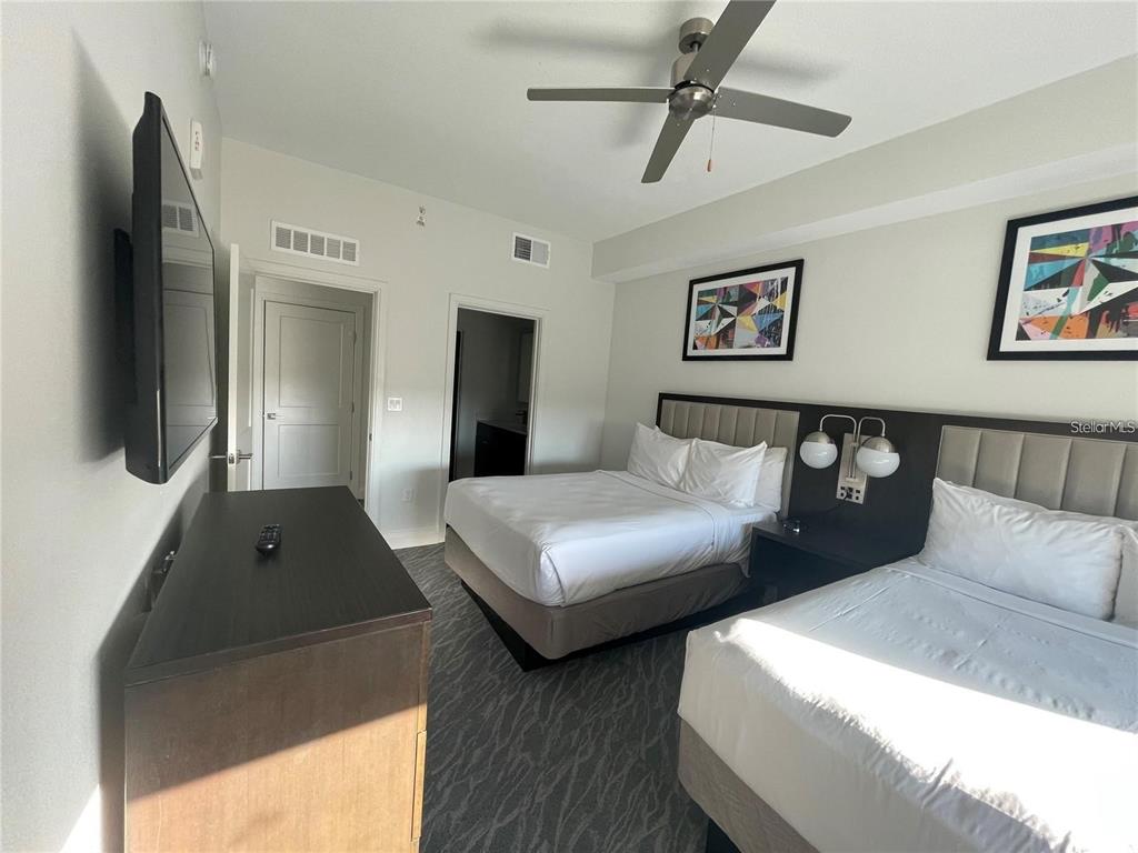A hotel bedroom features two beds, a television, and a ceiling fan — 14501 GROVE RESORT AVENUE, WINTER GARDEN, FL