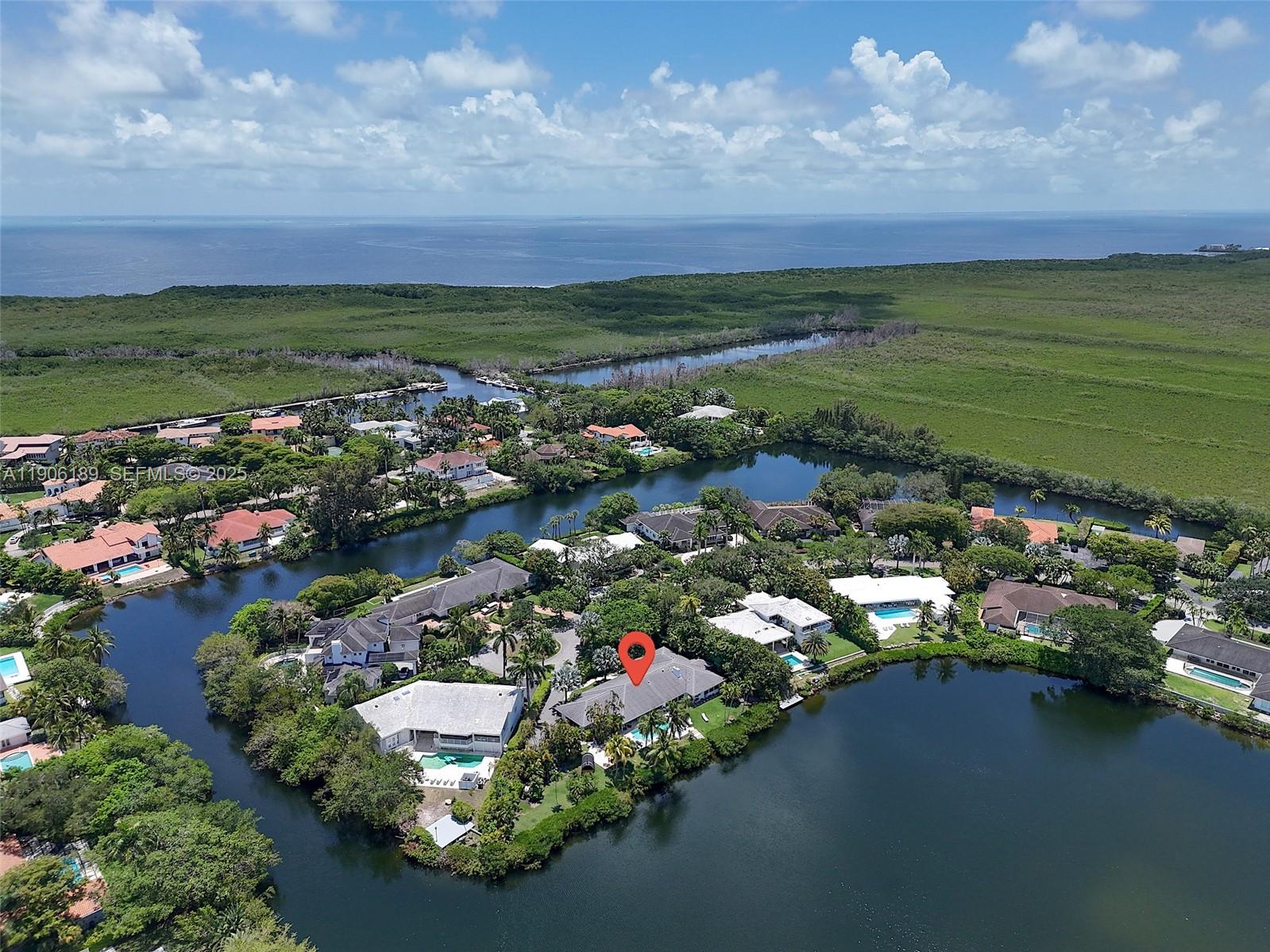 An aerial view shows a residential neighborhood with houses situated along a winding canal — 415 Rovino Ave, Coral Gables FL 33156, CORAL GABLES, FL