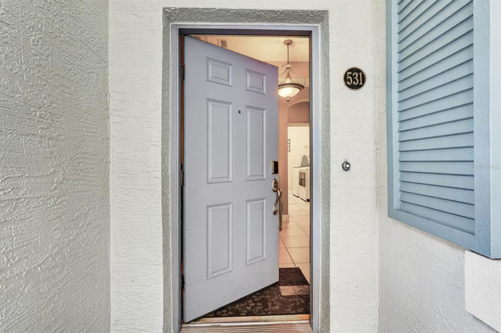 An open front door reveals a tiled entryway with a hanging light fixture inside — 600 CINNAMON BEACH WAY UNIT 531, PALM COAST, FL
