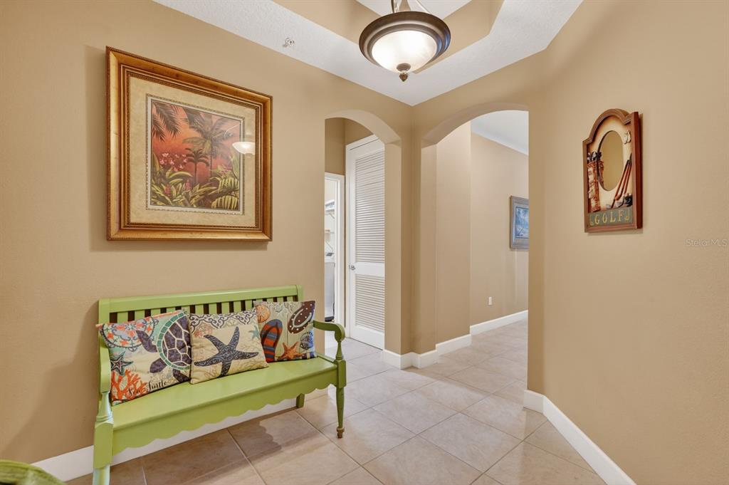 A hallway with tan walls, tile flooring, a green bench, and arched doorways — 600 CINNAMON BEACH WAY UNIT 531, PALM COAST, FL