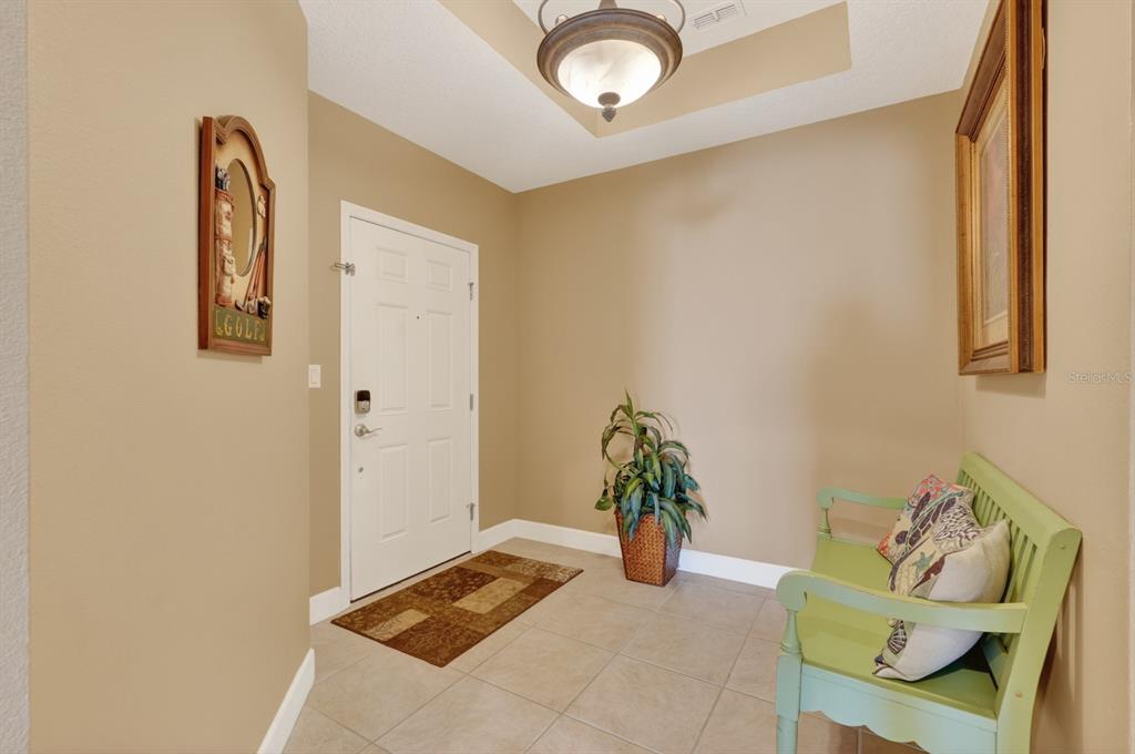 An entryway features a white front door, tile flooring, a light green bench, and decor — 600 CINNAMON BEACH WAY UNIT 531, PALM COAST, FL