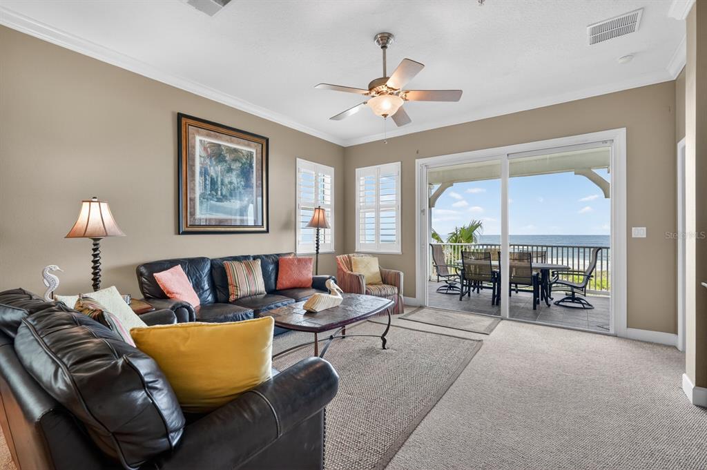 A living room with dark leather sofas, a ceiling fan, and a balcony overlooking the ocean — 600 CINNAMON BEACH WAY UNIT 531, PALM COAST, FL