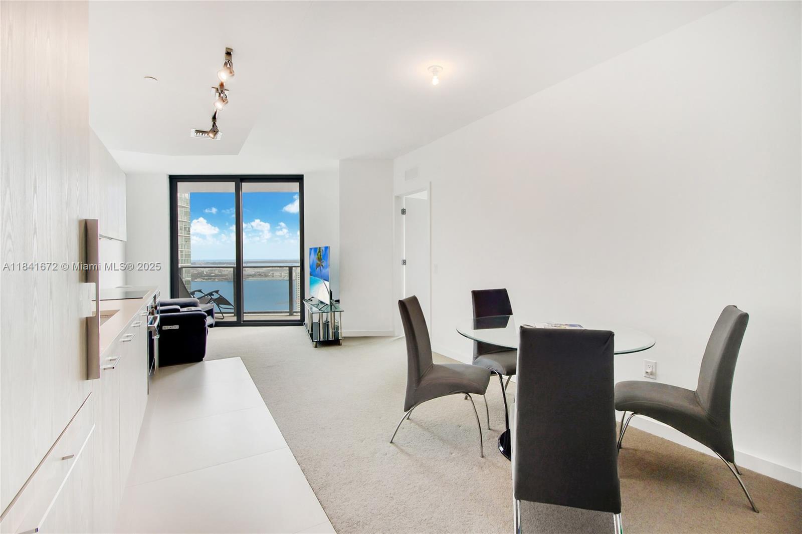 A modern apartment living area features a kitchen, dining set, and balcony with water views — 501 NE 31st St # 3607, Miami FL 33137, MIAMI, FL