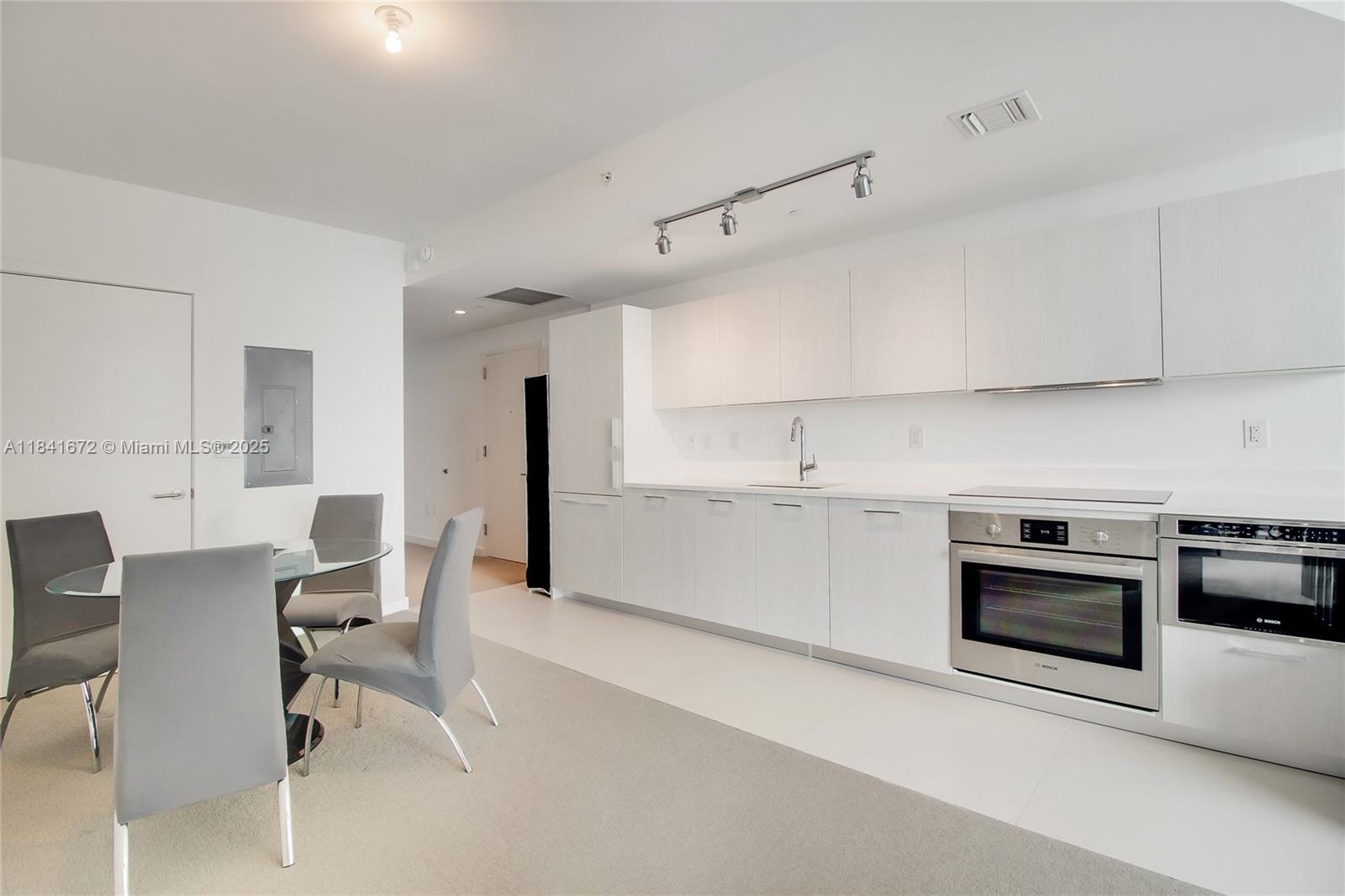 A modern kitchen features white cabinetry, stainless steel appliances, and an adjacent dining area — 501 NE 31st St # 3607, Miami FL 33137, MIAMI, FL