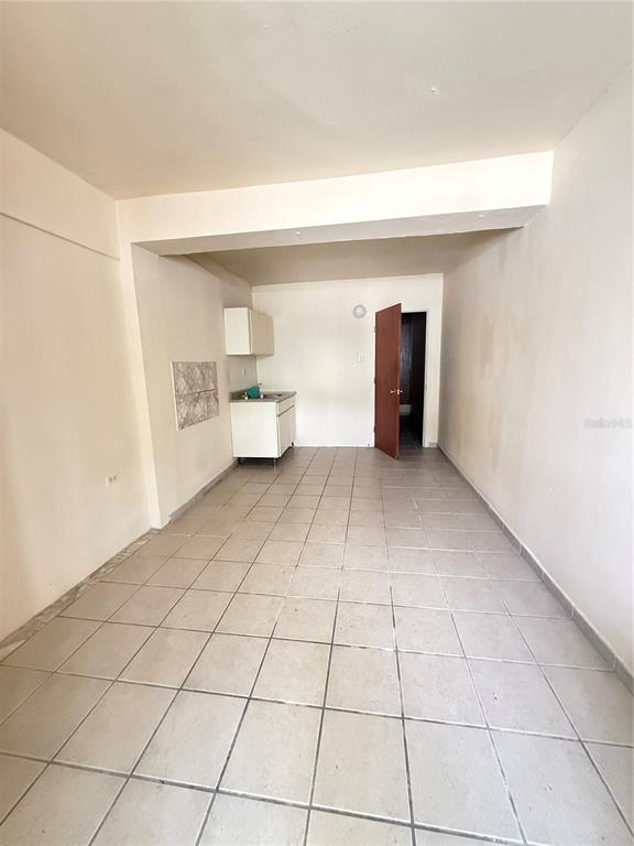 A small kitchen area with white cabinets and tiled floors leads to a doorway — Bo.Palmas CALLE CUCHARILLAS UNIT 228, CATANO, PR