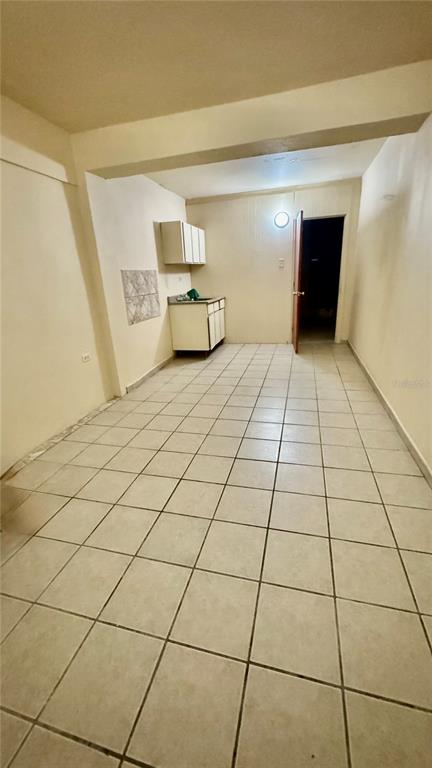 A small kitchen area with white cabinets and tiled floors sits at the end of a room — Bo.Palmas CALLE CUCHARILLAS UNIT 228, CATANO, PR