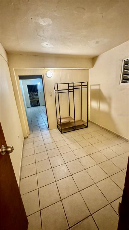 A room with light-colored tile flooring, a metal garment rack, and a doorway leading outside — Bo.Palmas CALLE CUCHARILLAS UNIT 228, CATANO, PR