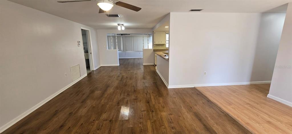 An open-concept living area features wood-look flooring, light gray walls, and a kitchen pass-through window — 3602 HARBOR BOULEVARD, PORT CHARLOTTE, FL
