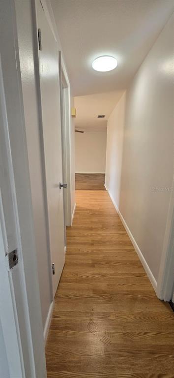 A narrow hallway with light wood-look flooring leads toward an open living area — 3602 HARBOR BOULEVARD, PORT CHARLOTTE, FL