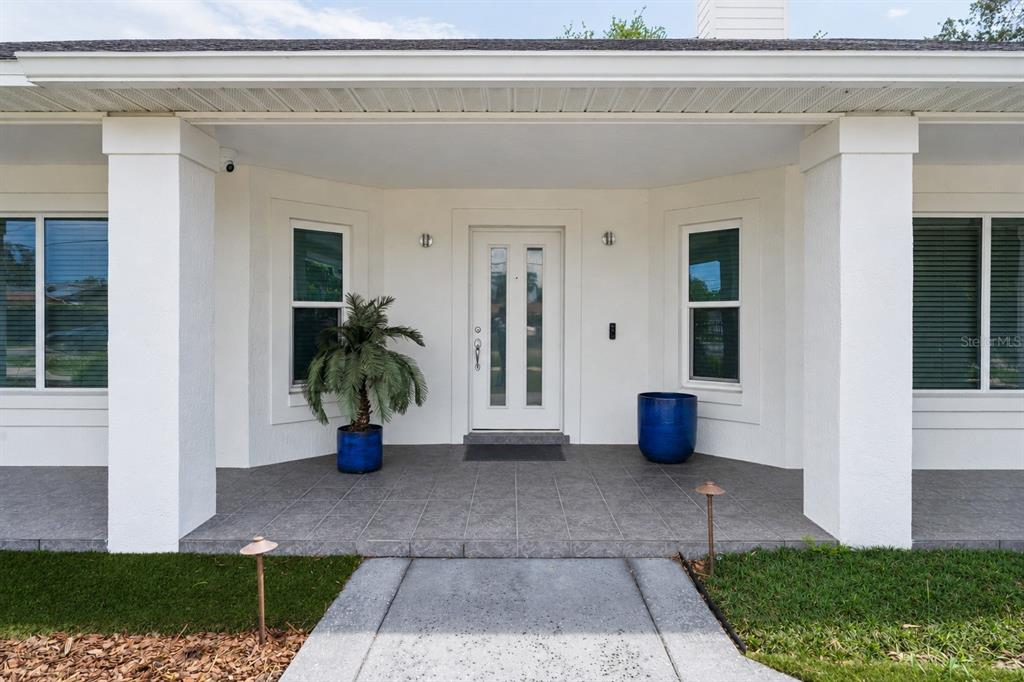 The exterior of a house features a covered porch with a white door and columns — 4404 SIMMONS ROAD, ORLANDO, FL