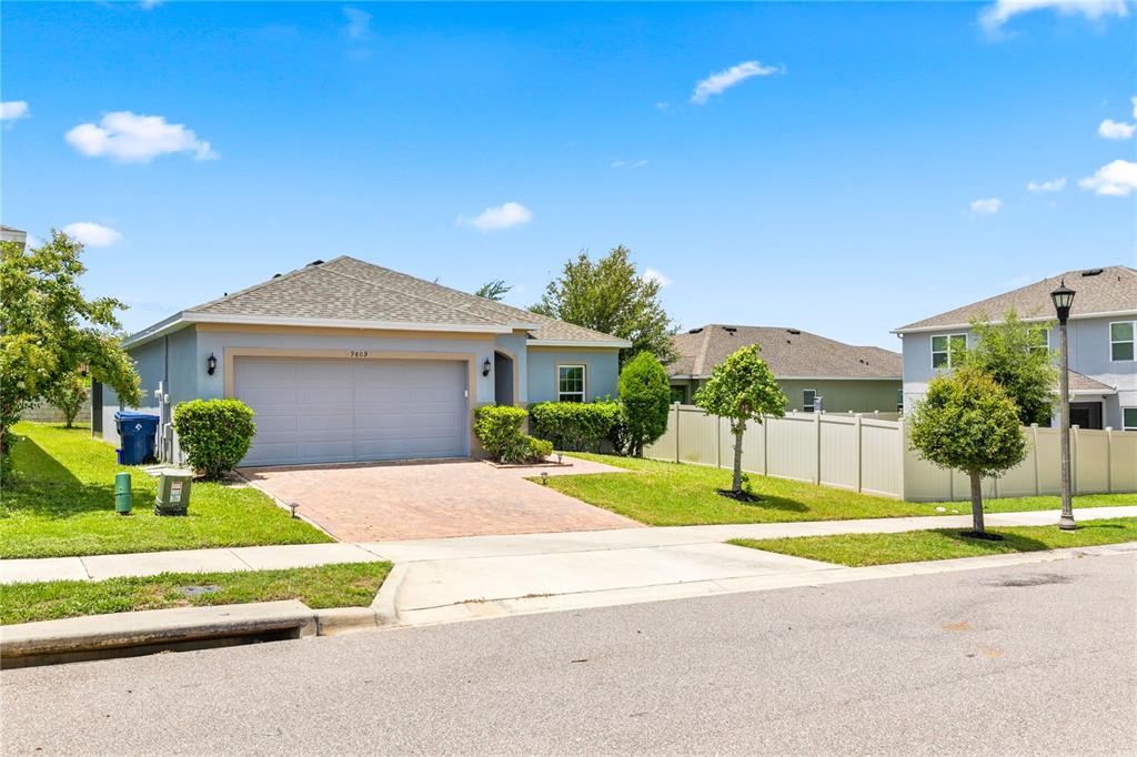 A single-story house with a gray garage, tan stucco walls, and a paved driveway — 9809 LATE WAY, GROVELAND, FL
