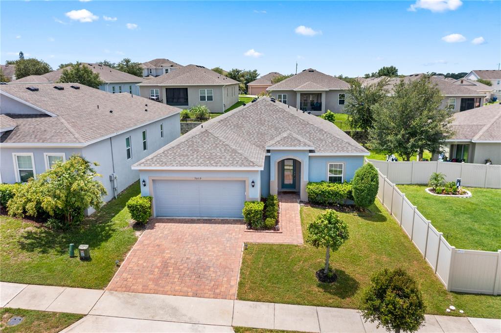 An aerial view shows a light blue single-story house with a brick driveway and walkway — 9809 LATE WAY, GROVELAND, FL