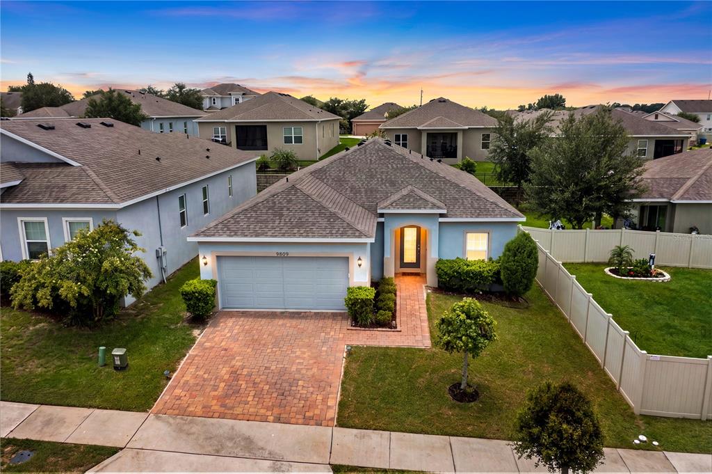 An aerial view of a single-story suburban house with a brick driveway and fenced yard — 9809 LATE WAY, GROVELAND, FL