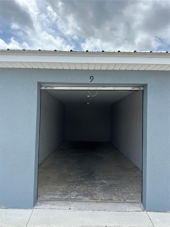 An open, empty garage unit with a concrete floor and a number nine above it — 110 SPIRIT LAKE ROAD UNIT 9, WINTER HAVEN, FL