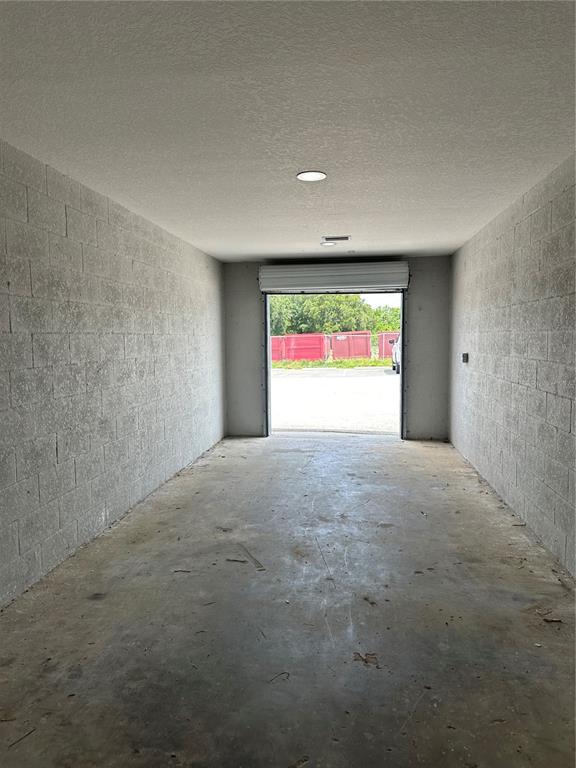 An interior view of a concrete block storage unit with a roll-up metal door — 110 SPIRIT LAKE ROAD UNIT 9, WINTER HAVEN, FL