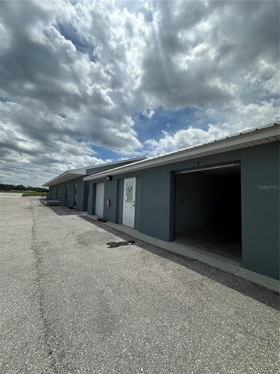 An exterior view of a gray commercial building with multiple storage unit doors and entrances — 110 SPIRIT LAKE ROAD UNIT 9, WINTER HAVEN, FL