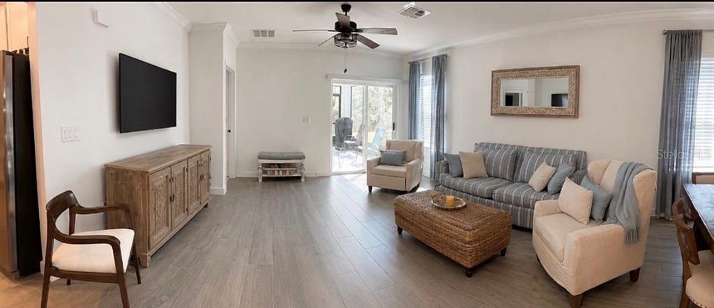 A living room features light wood-look tile flooring, a striped sofa, and a wooden media console — 16890 FORGE SURF STREET, LAND O LAKES, FL